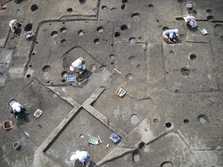 幾重にも重複する竪穴建物跡を発掘調査する様子の写真